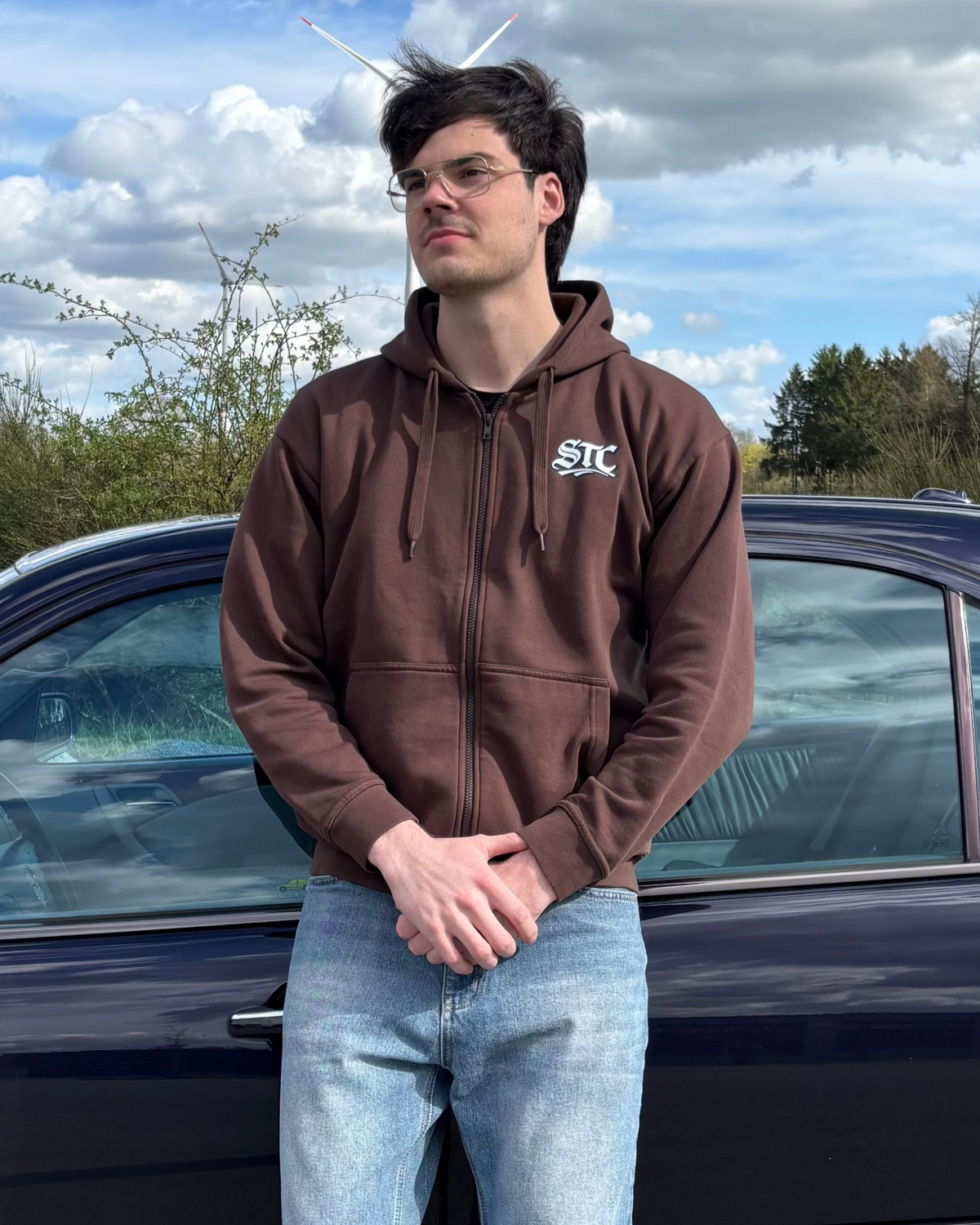 Junger Mann hat Save The Classics Zip Hoodie an und steht vor einem lila W210